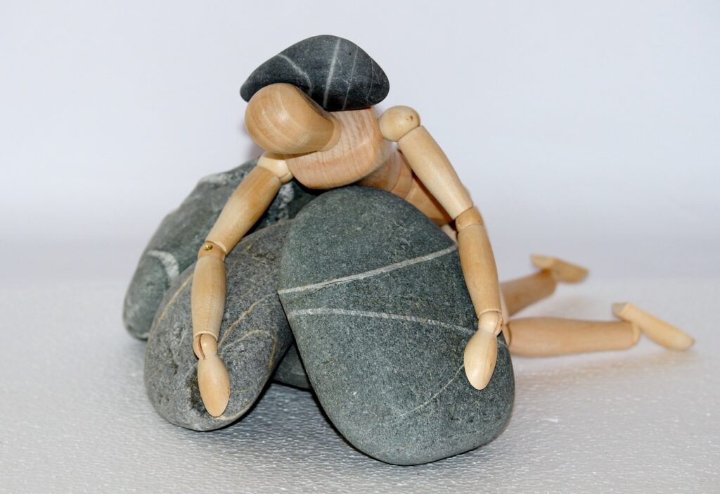 burnout; wooden figure weighted by rocks